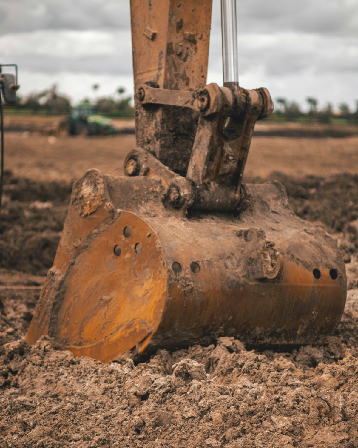 Excavator bucket resting in freshly dug soil on a job site